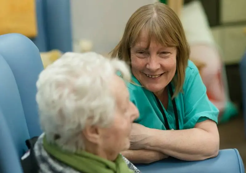 A carer smiling with an older woman in her armchair